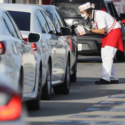 A worker in a face mask takes orders from motorists in the drive-through lane at a burger restaurant on July 1 in Los Angeles, California. California governor Gavin Newsom has ordered indoor dining restaurants to close again for at least three weeks amid a surge in new coronavirus cases. Photo: AFP