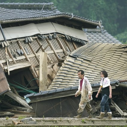 Residents walk beside a collapsed house in the flood-ravaged village of Kuma in Kumamoto prefecture, southwestern Japan. Photo: Kyodo