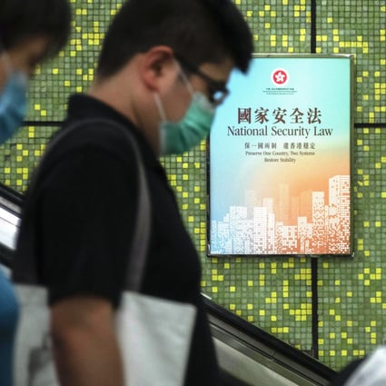A man passes by a national security law poster while riding down an escalator in Hong Kong. Photo: Bloomberg
