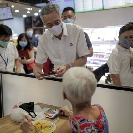 Singapore Prime Minister Lee Hsien Loong, centre, speaks to a woman at a food court during a campaign walkabout on July 1. Photo: EPA