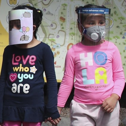 Girls wearing face shields wait for their parents before entering a zoo on the outskirts of Quito, Ecuador on Wednesday. Photo: AP