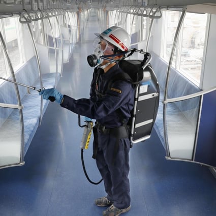 A Tokyo Metro worker, wearing goggles and protective mask, sprays antivirus inside a passenger car at its depot. Photo: Kyodo