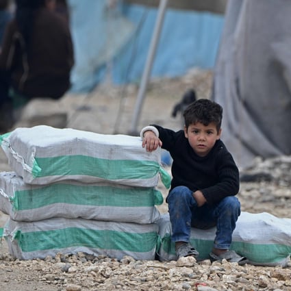A Syrian boy sits next to humanitarian aid in a camp on February 21. A UN Security Council resolution for a global ceasefire to allow coronavirus aid to the most vulnerable is mired in disagreement. Photo: AFP