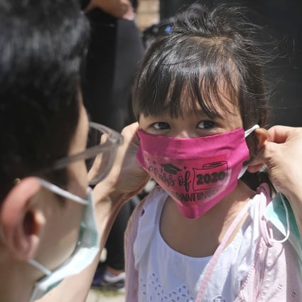 A man helps his daughter with a new mask she received during a graduation ceremony for her pre-K class in front of Bradford School in Jersey City, N.J. Photo: AP Photo