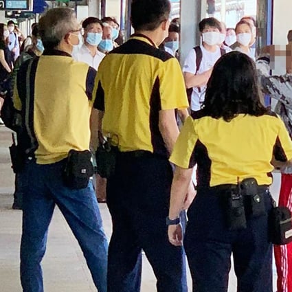 MTR staff at Tai Wan station surround a man who holds a stick over his head after refusing to wear a mask. Photo: Handout