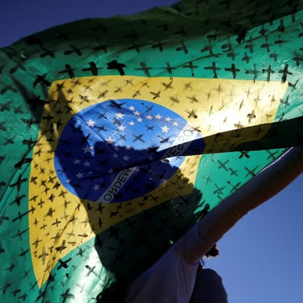 An activist holds a Brazilian flag painted with crosses symbolising people who died from Covid-19 in front of the National Congress in Brasilia on Tuesday. Photo: Reuters