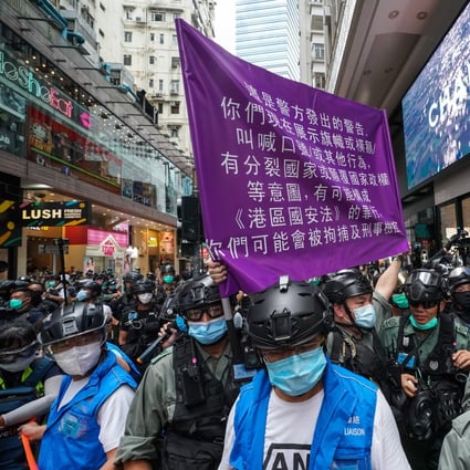 A Hong Kong police officer holds up a flag warning protesters they are violating the national security law, during a demonstration in Causeway Bay on July 1. Photo: Felix Wong