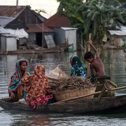 Women and children use a boat to make their way through floodwaters in Sunamganj in Bangladesh. Photo: AFP