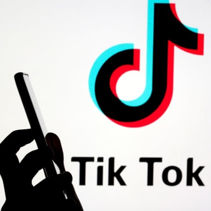 A woman holds a smartphone as a Tik Tok logo is displayed behind her. Since it was created in 2017, TikTok has become a staple of internet culture and social interaction for teenagers. Photo: Reuters