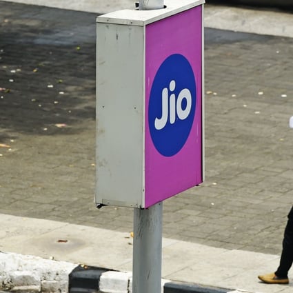 Commuters walk past a board advertising Reliance Jio in Mumbai on June 19, 2020. Photo: AFP