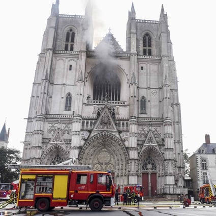 A French police officer directs traffic while firefighters work to put out a fire that broke out at Saint-Pierre-et-Saint-Paul cathedral in Nantes, causing serious damage. Photo: AFP