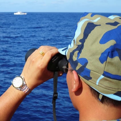 A crewman from a Vietnamese coastguard ship looks out at Chinese military vessels in the South China Sea in 2014. The countries’ disputes over the waterway go back decades. Photo: Reuters