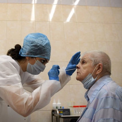 A medical worker wearing protective equipment takes a swab from a woman at a medical facility in Moscow. Photo: AFP