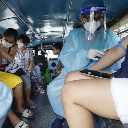 Health workers collect blood samples inside a jeepney bus at a free Covid-19 drive-through testing facility in Manila. Photo: AP