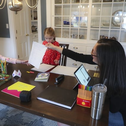 Sarah Yunits checks her daughter Ada’s homework while Cora waits her turn and father Conor Yunits takes a work call at their home in Brockton, Massachusetts, on March 19. Working from home has been a boon to many during the pandemic but has also posed personal and professional challenges during the transition. Photo: Getty Images