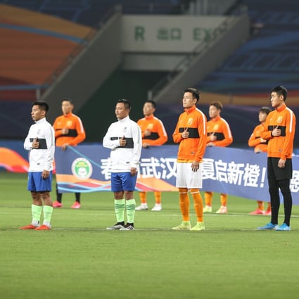 Players from both sides pay their respects for the medical workers fighting against Covid-19 ahead of the opening Chinese Super League match between Wuhan Zall and Qingdao Huanghai. Photo: Xinhua