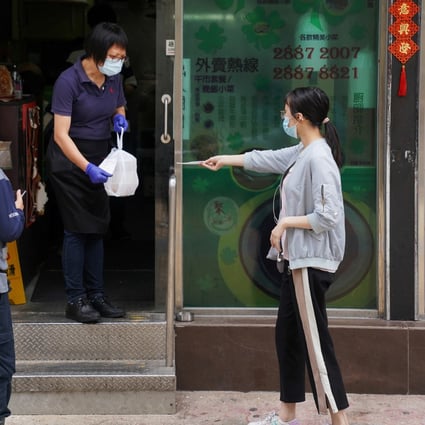 A staff member wearing a face mask hands takeaway food to a customer outside a restaurant in Hong Kong. Photo: Reuters