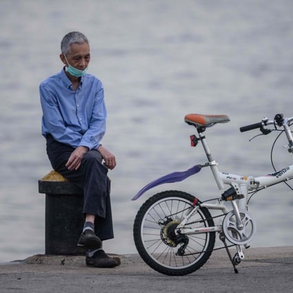 An elderly man rests next to his bicycle on a cargo dock in Hong Kong on April 21. Older adults living alone continue to struggle as Hong Kong grapples with a third Covid-19 wave. Photo: AFP