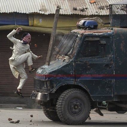A masked Kashmiri protester jumps on the bonnet of an armoured Indian police vehicle during a May 2019 demonstration in Srinagar. Photo: AP