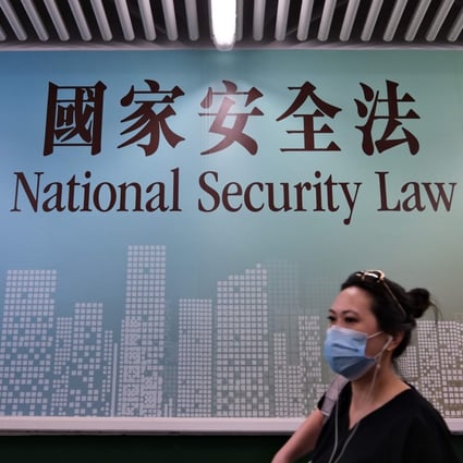 A woman walks past a poster for the National Security Law in Hong Kong in July. Photo: AFP