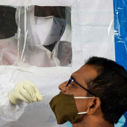 A health worker collects a swab from a resident at a makeshift coronavirus testing booth in Hyderabad on Monday. Photo: AFP