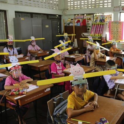 A teacher and students wearing hats designed for space keeper, practice social distancing to help curb the spread of the coronavirus. Photo: AP