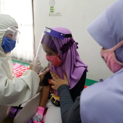 A doctor wearing a hazmat suit pictured administering a vaccine for a patient in Depok, Indonesia. Photo: EPA