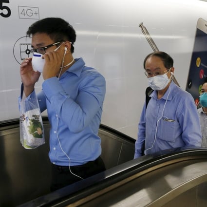 Singaporean officer workers wearing masks leave a train station during the morning commute. Photo: Reuters