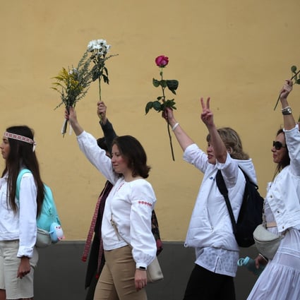 Women hold flowers aloft during a rally on Thursday in Minsk in support of protesters detained and injured in the aftermath of Sunday’s disputed presidential election. Photo: EPA