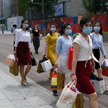 Women have become a driving force of consumption in China. Here, women wearing walk along a business street after shopping in Beijing. Photo: Agence France-Presse)