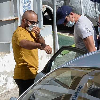 A man with a blue cap, believed to be Manchester United captain Harry Maguire, is escorted by plain-clothes police officers to the police station of the island of Syros, Greece, Photo: Reuters