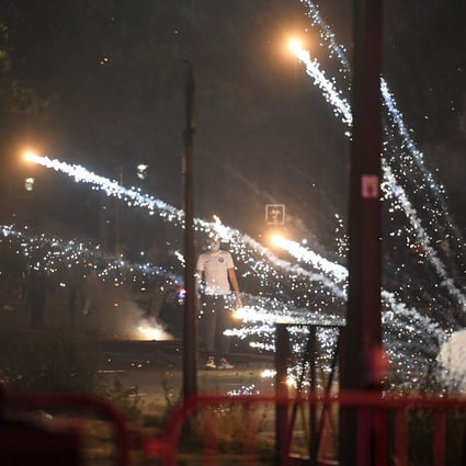 A man is pictured as tear gas canisters explode around him following a night of violence on the streets of Paris after PSG’s loss to Bayern Munich. Photo: AFP