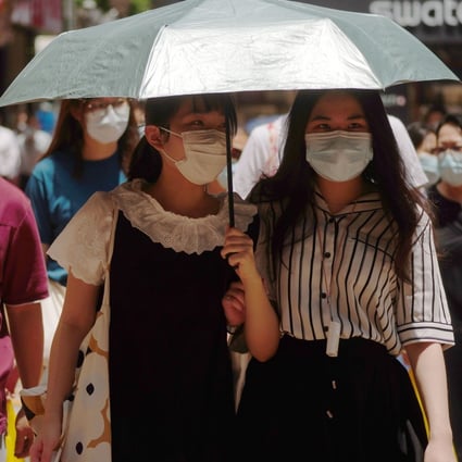 Pedestrians use an umbrella to shield themselves from the sun as they walk down the street on Monday. Photo: Sam Tsang