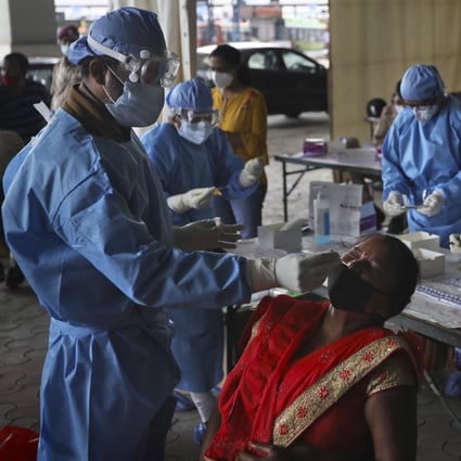 Health workers conduct Covid-19 antigen tests for migrant workers in New Delhi, India. Photo: AP