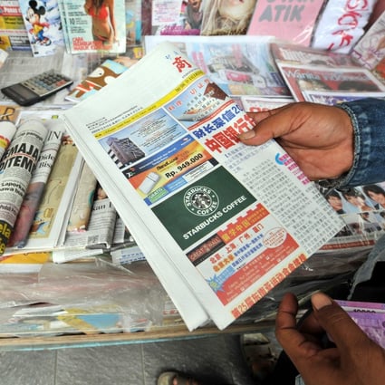 A vendor holds a copy of the ‘Indonesia Shangbao’ newspaper in Jakarta. Photo: AFP