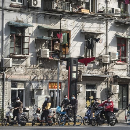 Moped riders and cyclists wearing masks wait at a traffic light in Shanghai on April 2. Photo: Bloomberg
