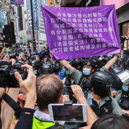 A police officer raises a flag warning protesters they could be in violation of the new national security law in Causeway Bay on July 1. Photo: Sam Tsang