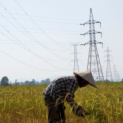 A farmer works in a paddy field under power lines in Laos’ Khammouane province in this 2013 file photo. Photo: Reuters