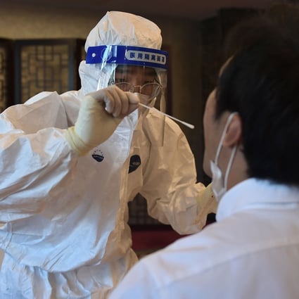 A worker in a protective suit takes a swab to test for Covid-19. Photo: AFP