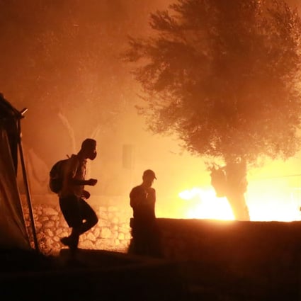 Migrants are seen leaving as a fire burns in the Moria camp on the island of Lesbos, Greece. Photo: AFP