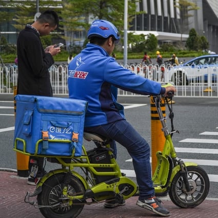 A Ele.me delivery driver waits to cross the pedestrian crossing in the Futian district in Shenzhen, 2019. Photo: SCMP/Roy Issa
