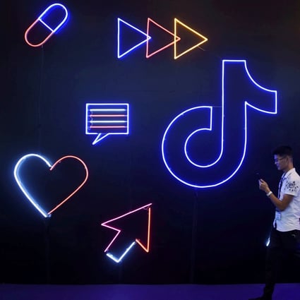 A man holding a phone walks past a sign for TikTok, known in China as Douyin. Photo: Reuters