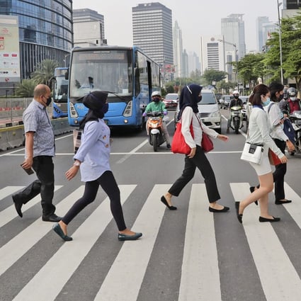 Jakarta residents wearing face masks as a precaution against Covid-19 cross the road in the capital’s central business district. Photo: AP