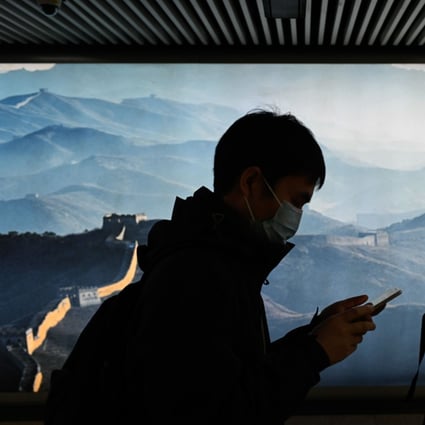 A man and a woman wearing face masks use their mobile phone as they walk in a subway station in Beijing on March 11. Picture: AFP