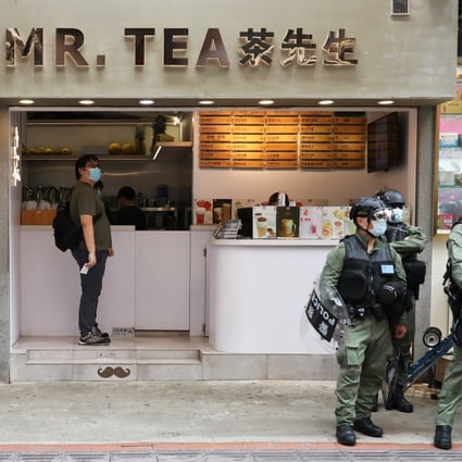 A man orders a drink at a tea shop as police officers stand outside in Causeway Bay on Thursday. Photo: Nora Tam