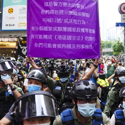 Police hold up a flag warning against breaches to the national security law in Causeway Bay on Thursday. Photo: Sam Tsang