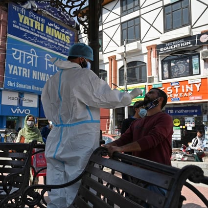A medical worker collects a swab sample from a man in Srinagar, India. Photo: AFP