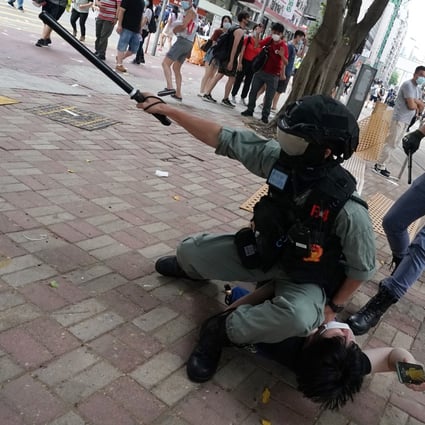 A police officer points with his baton as he holds down an anti-government protester during an illegal demonstration in July. Photo: Felix Wong