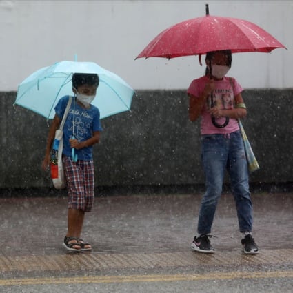 Children wait to cross the road in Cheung Sha Wan amid a heavy downpour on September 15. Photo: Xiaomei Chen