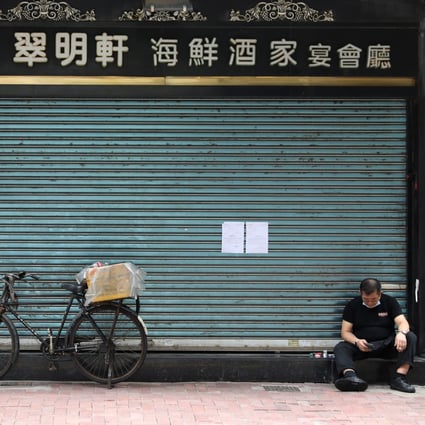 A man sits with his face mask down outside a closed restaurant in Causeway Bay amid the third wave of coronavirus infections. Photo: Nora Tam